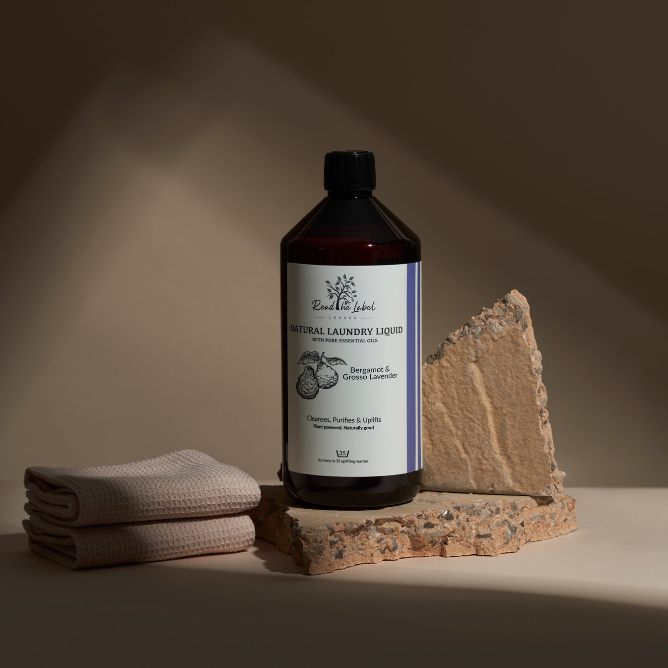 Bottle of natural laundry liquid with a towel and stone on a neutral background