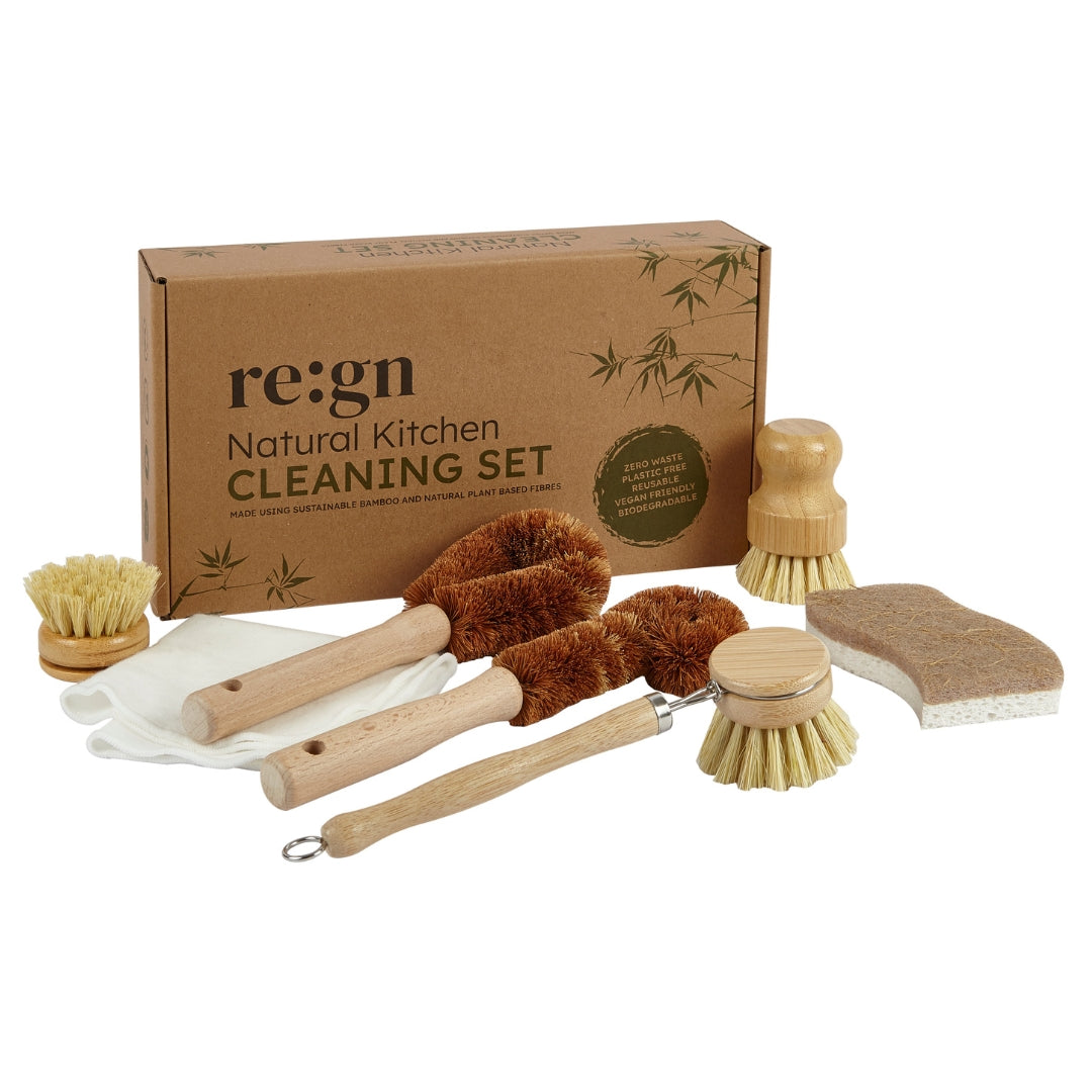 A natural kitchen cleaning set displayed in front of its brown cardboard packaging box. The set includes wooden-handled cleaning brushes, a sponge, a white cloth, and a small brush, all arranged on a clean white background.