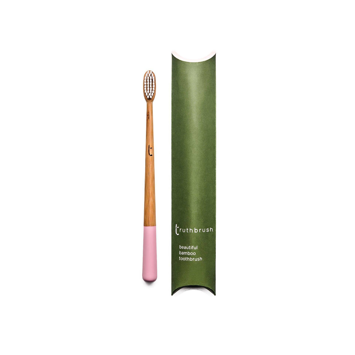 Pink handled plastic-free amboo toothbrush with pink base and green plastic-free packaging on a white background
