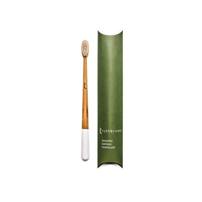 Bamboo handled toothbrush with plastic free bristles white tip next to plastic free gree packaging