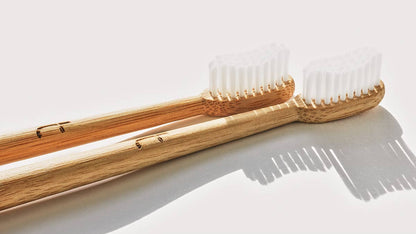 Two bamboo toothbrushes with clear plastic-free bristles on a light background