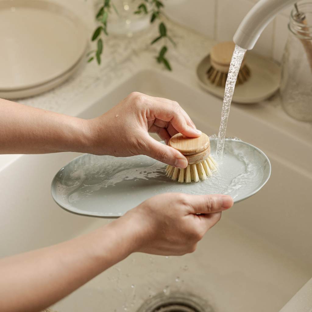 Person washing a plate with a sponge in a sink